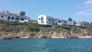 A coastal building with multiple balconies, situated on a rocky shoreline with clear blue water in the foreground. - Beach house with large garden (Seaside Paradise Vasto) (Vasto)