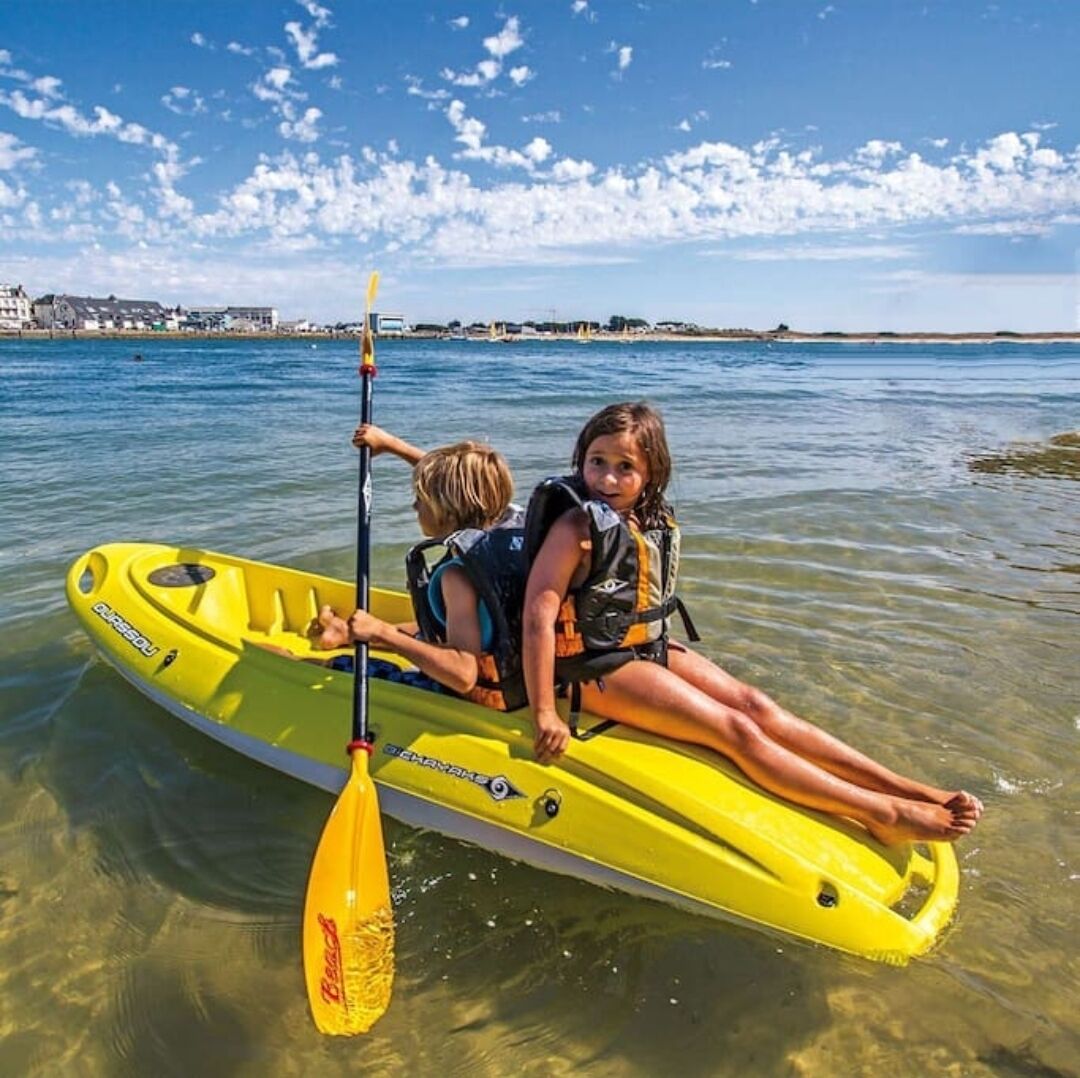 Dos personas en un kayak amarillo sobre aguas claras, con una orilla lejana.