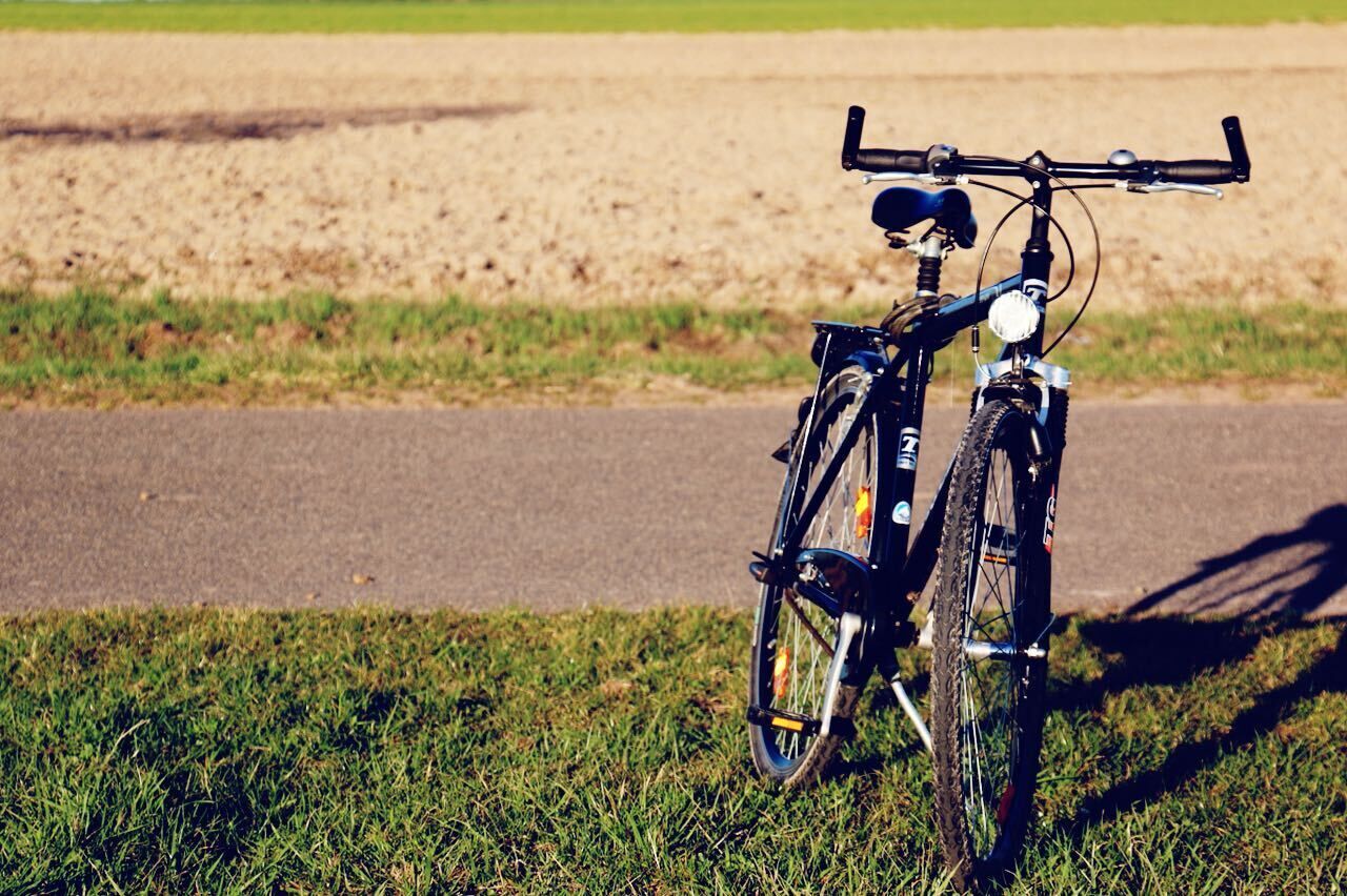 A bicycle parked on a grassy area beside a paved road.