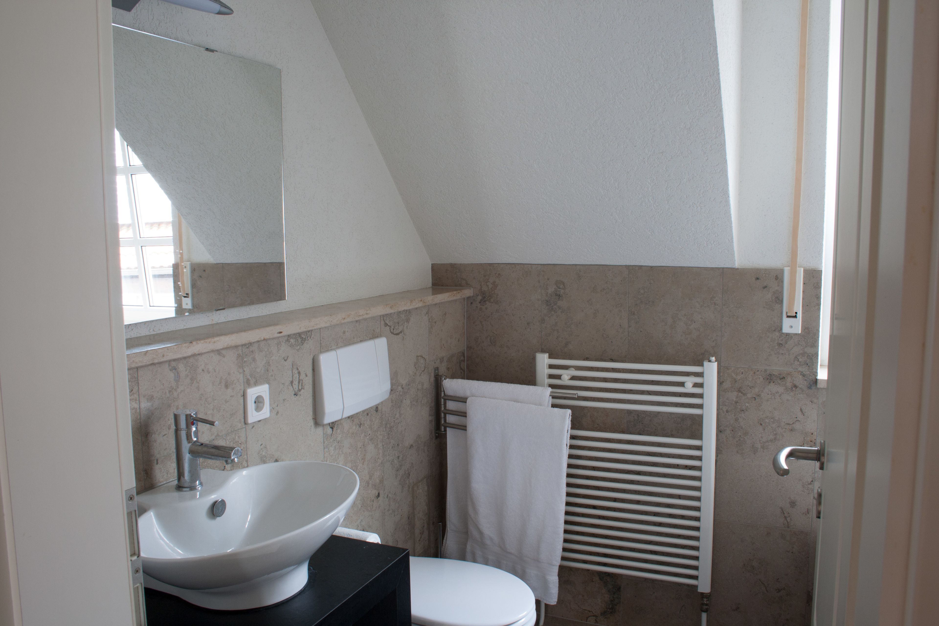 A bathroom with a white sink, a toilet, a towel rack, and a mirror.