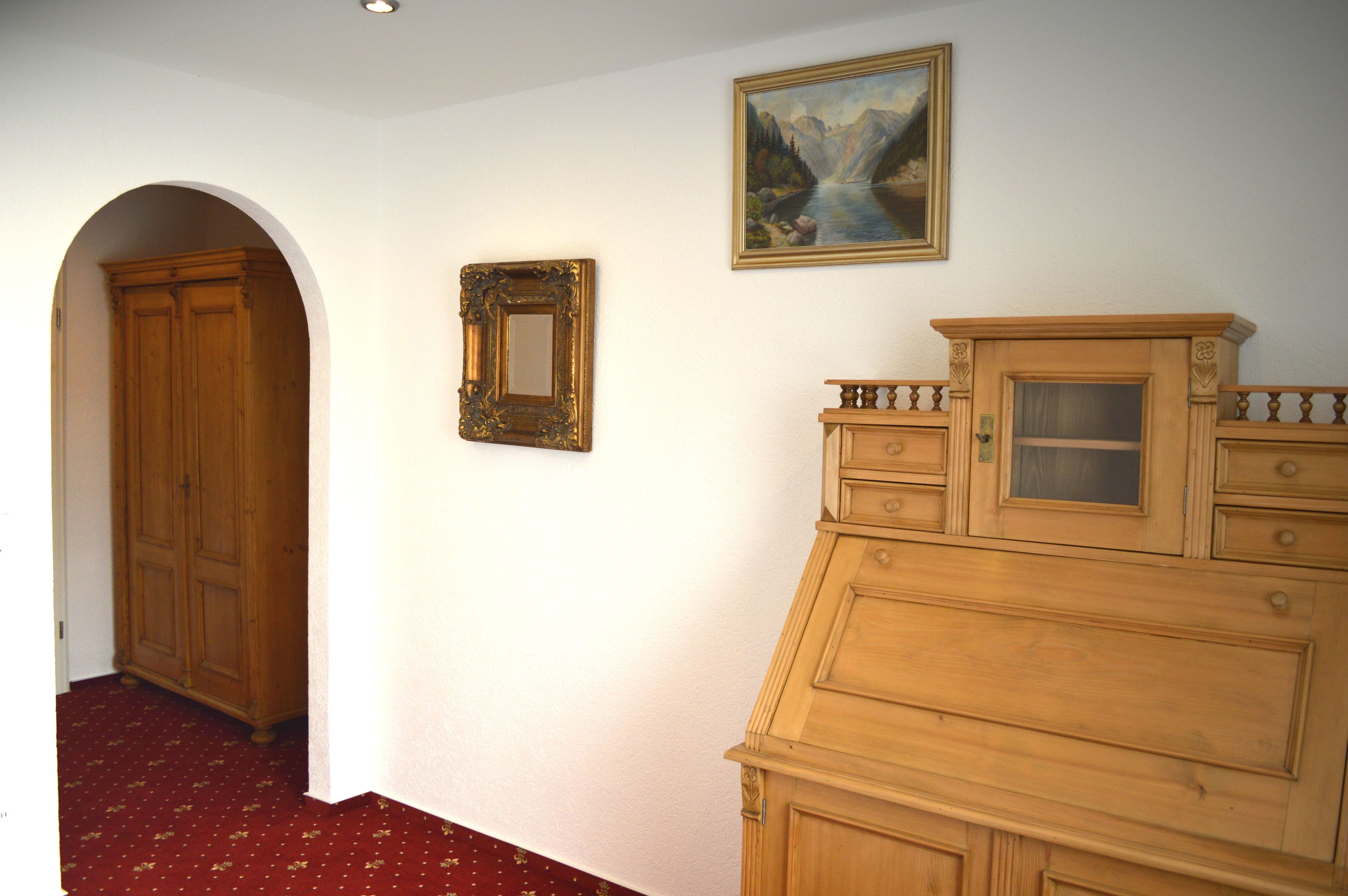 A hallway with a wooden wardrobe, a mirror, and a painting on the wall.