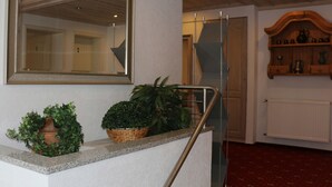 Una escalera con barandilla metálica, un espejo en la pared y plantas en macetas en el rellano.