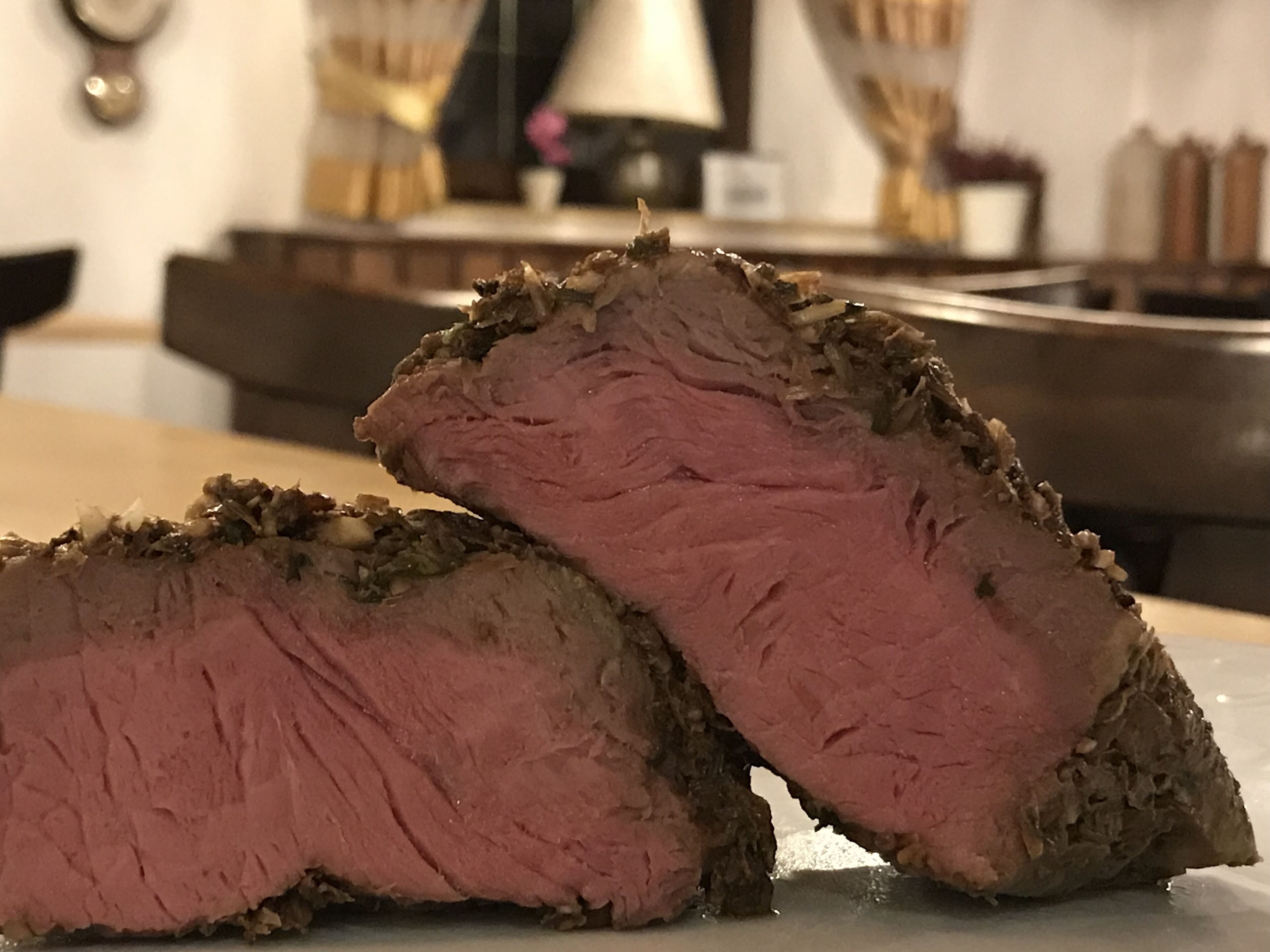 Un filete de res a término medio, jugoso y con una costra de hierbas y especias, servido en un plato blanco.