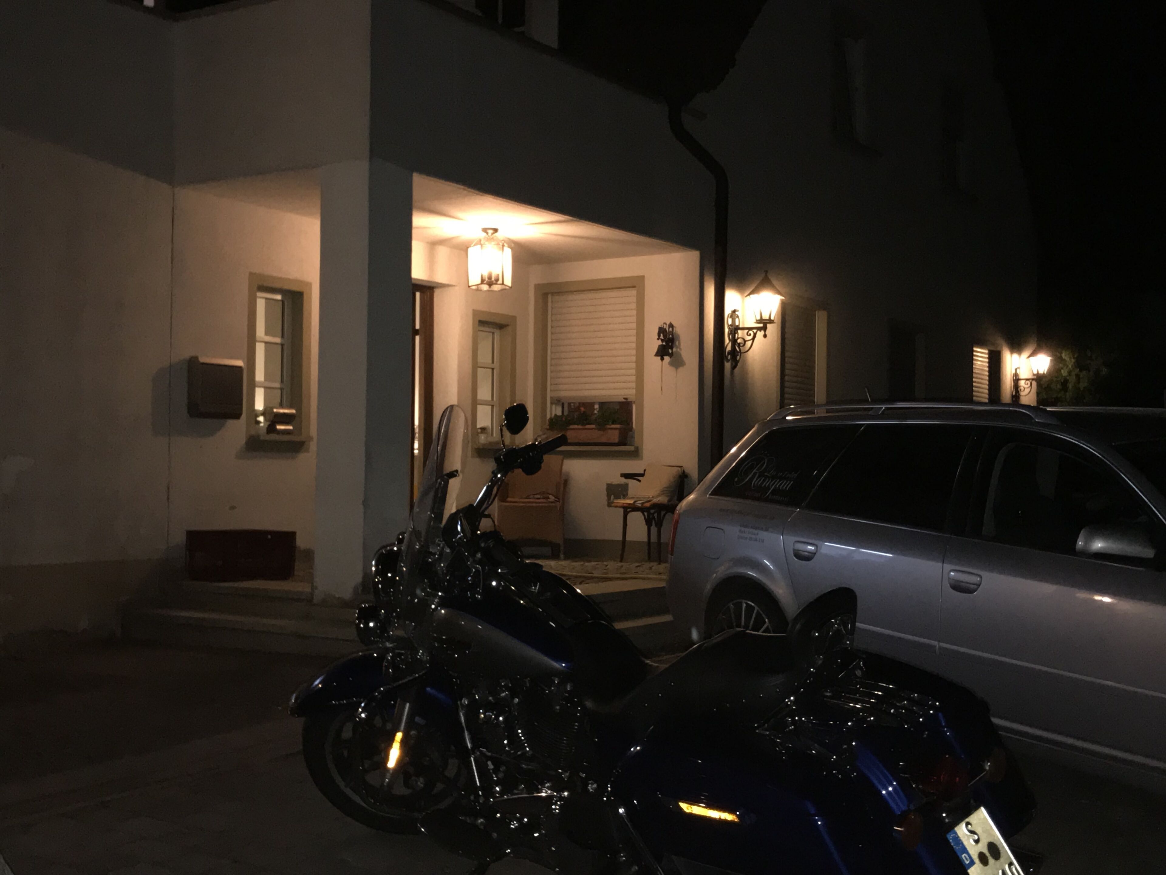Una motocicleta estacionada frente a una casa, con un automóvil aparcado a su lado.