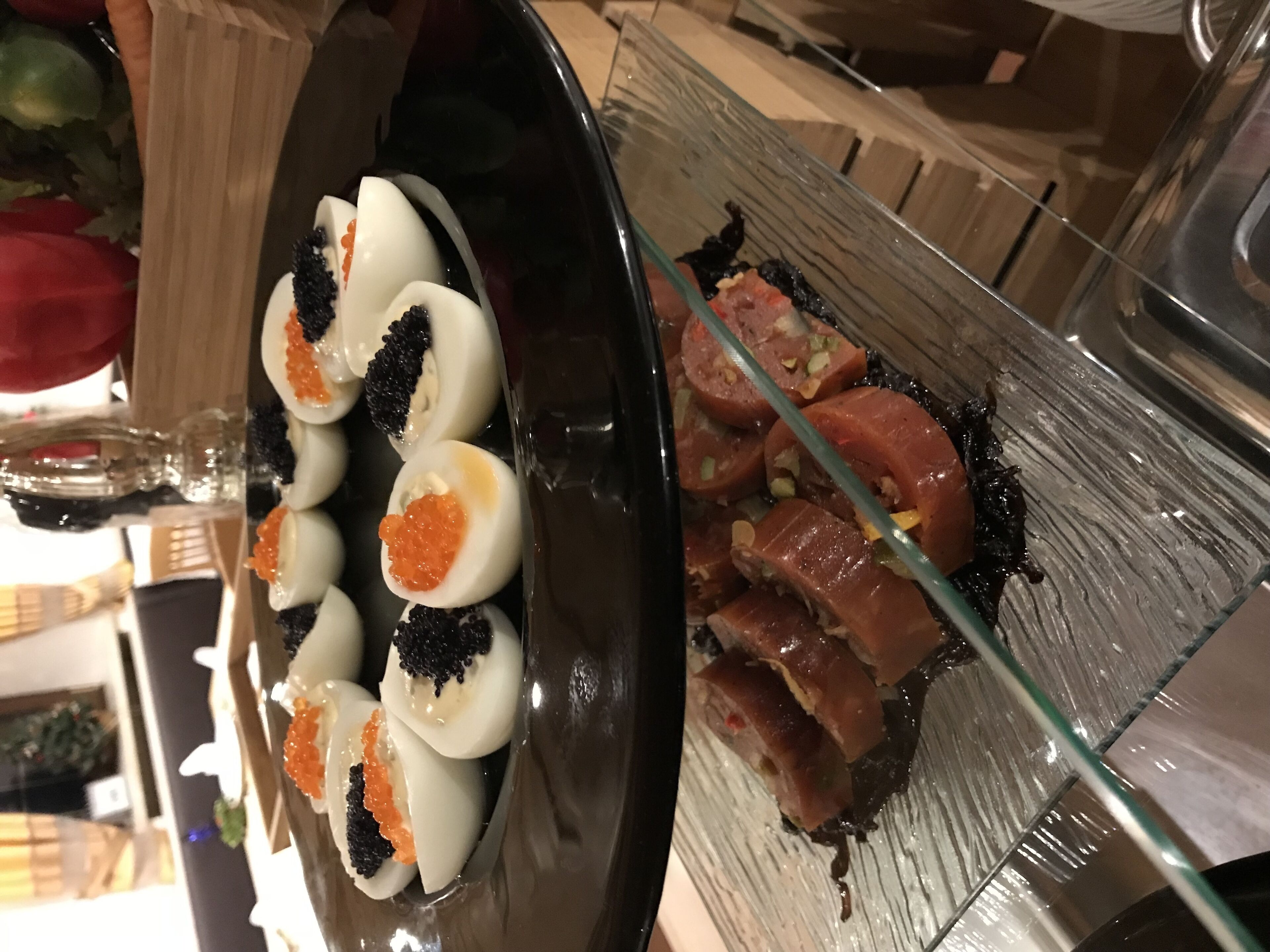 Une vitrine en verre contenant des tranches de saumon et des œufs durs, le tout garni de caviar.