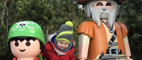 Criança com casaco vermelho e uma estátua de pirata com barba e chapéu.