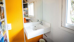 Een badkamer met een wit wastafelmeubel, spiegel en raam.