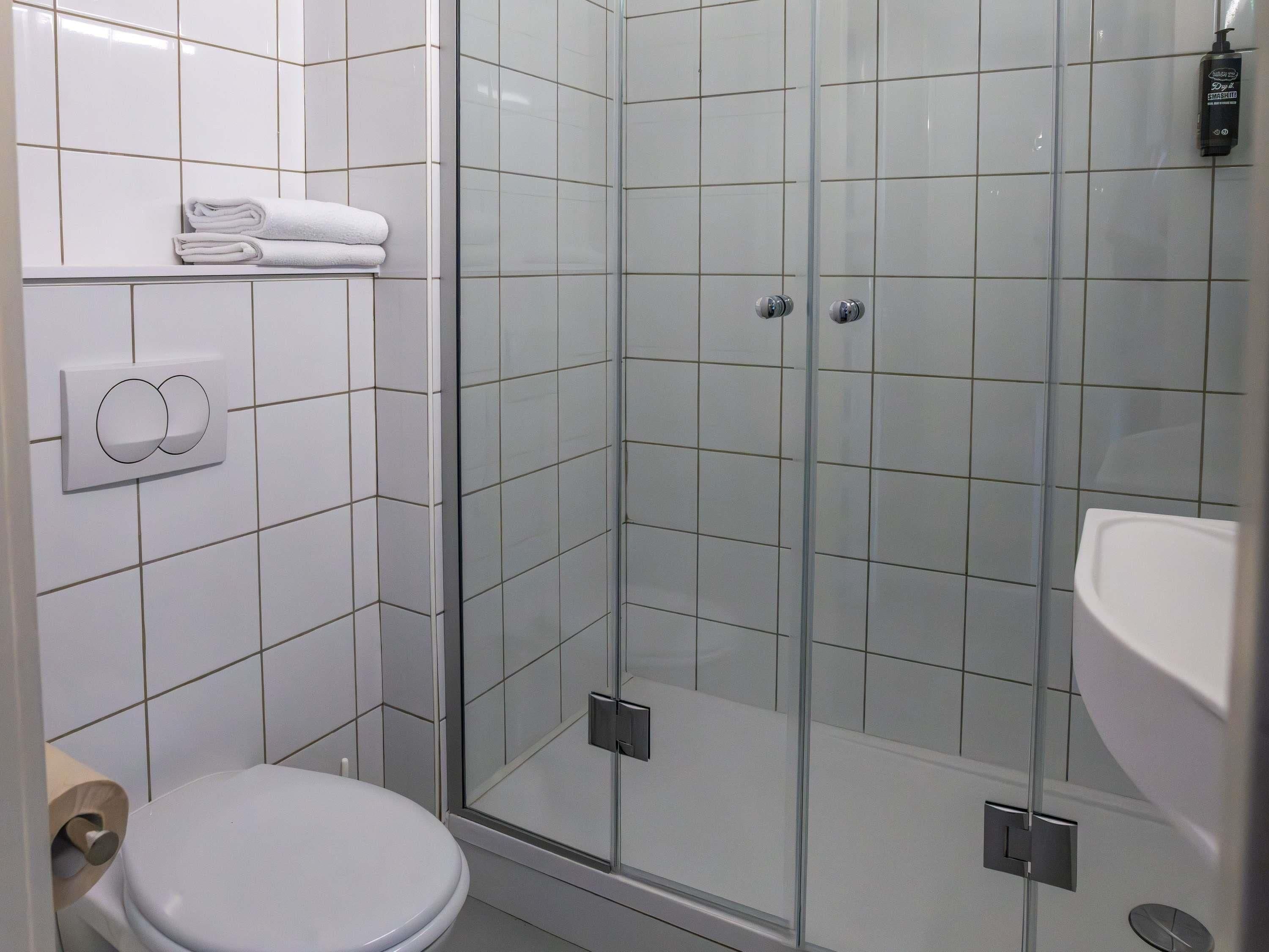 A modern bathroom with a glass-enclosed shower, a toilet, and a sink.