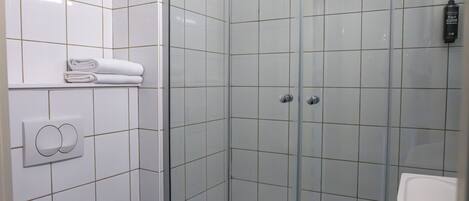 Un baño moderno con ducha de vidrio, inodoro y lavamanos.