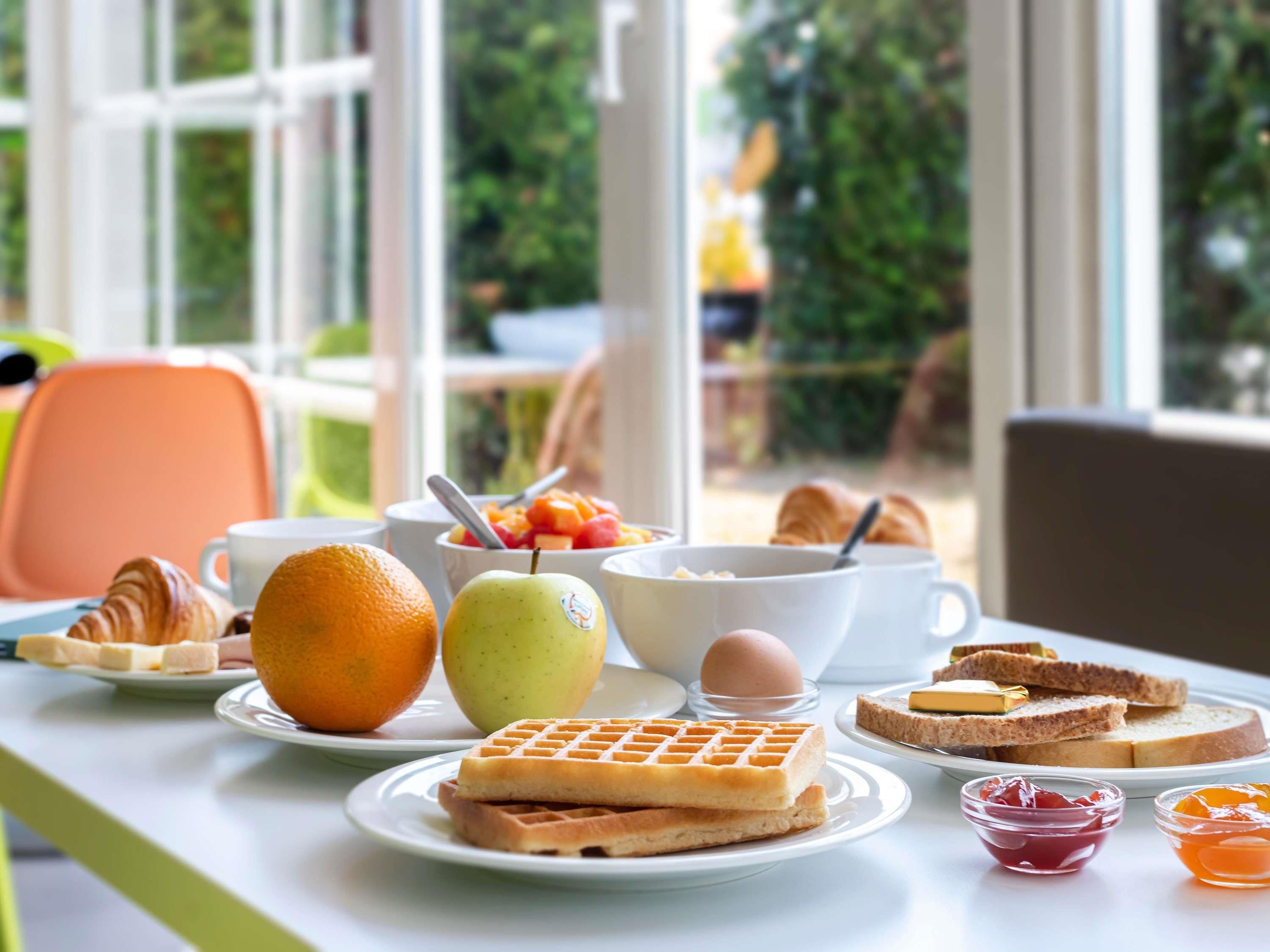 Een ontbijttafel met wafels, fruit, eieren en toast.