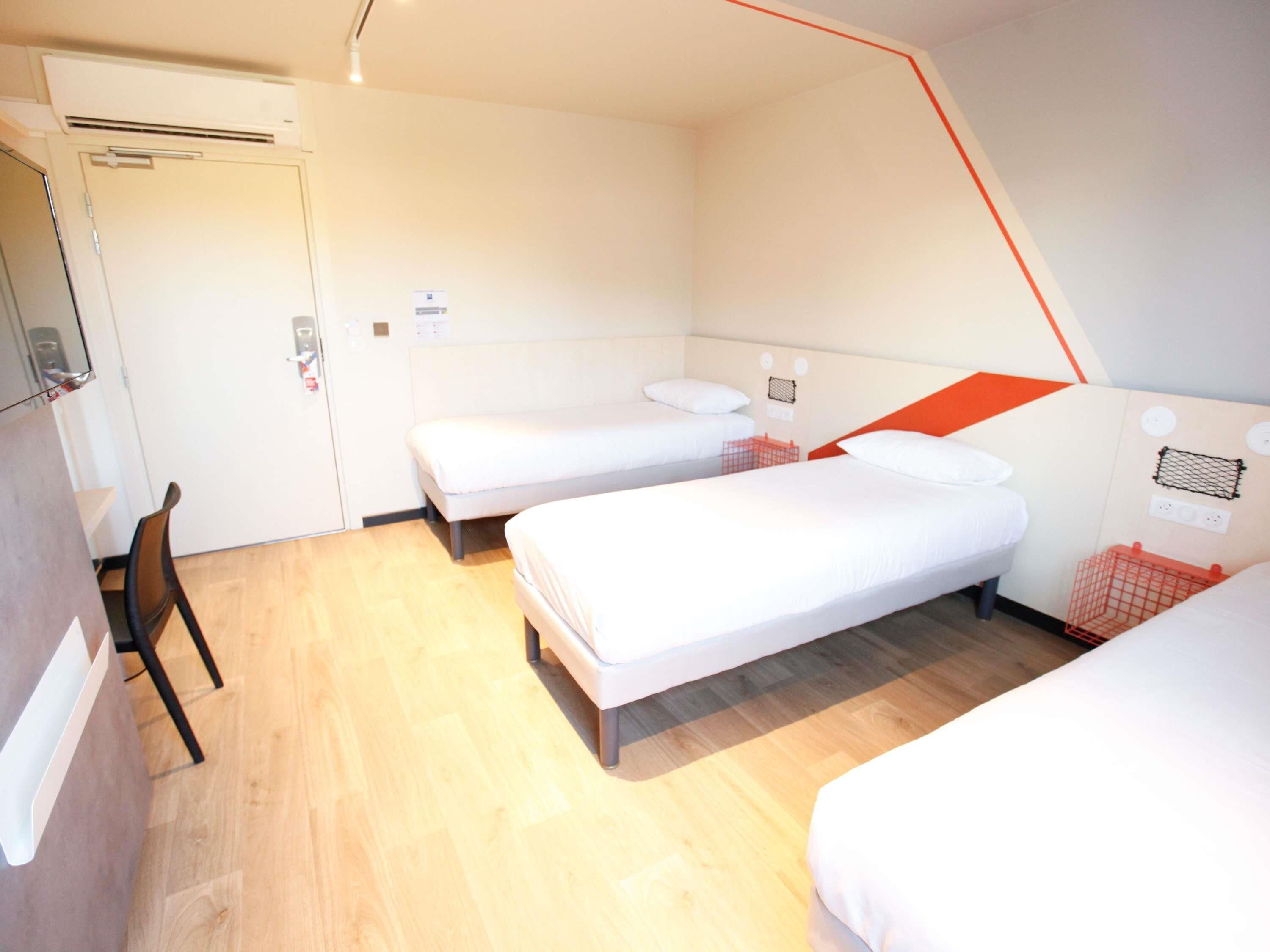 A room with two single beds, a chair, and a desk.