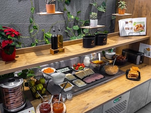 Montaje de bufé con diferentes alimentos, salsas y un tostador.