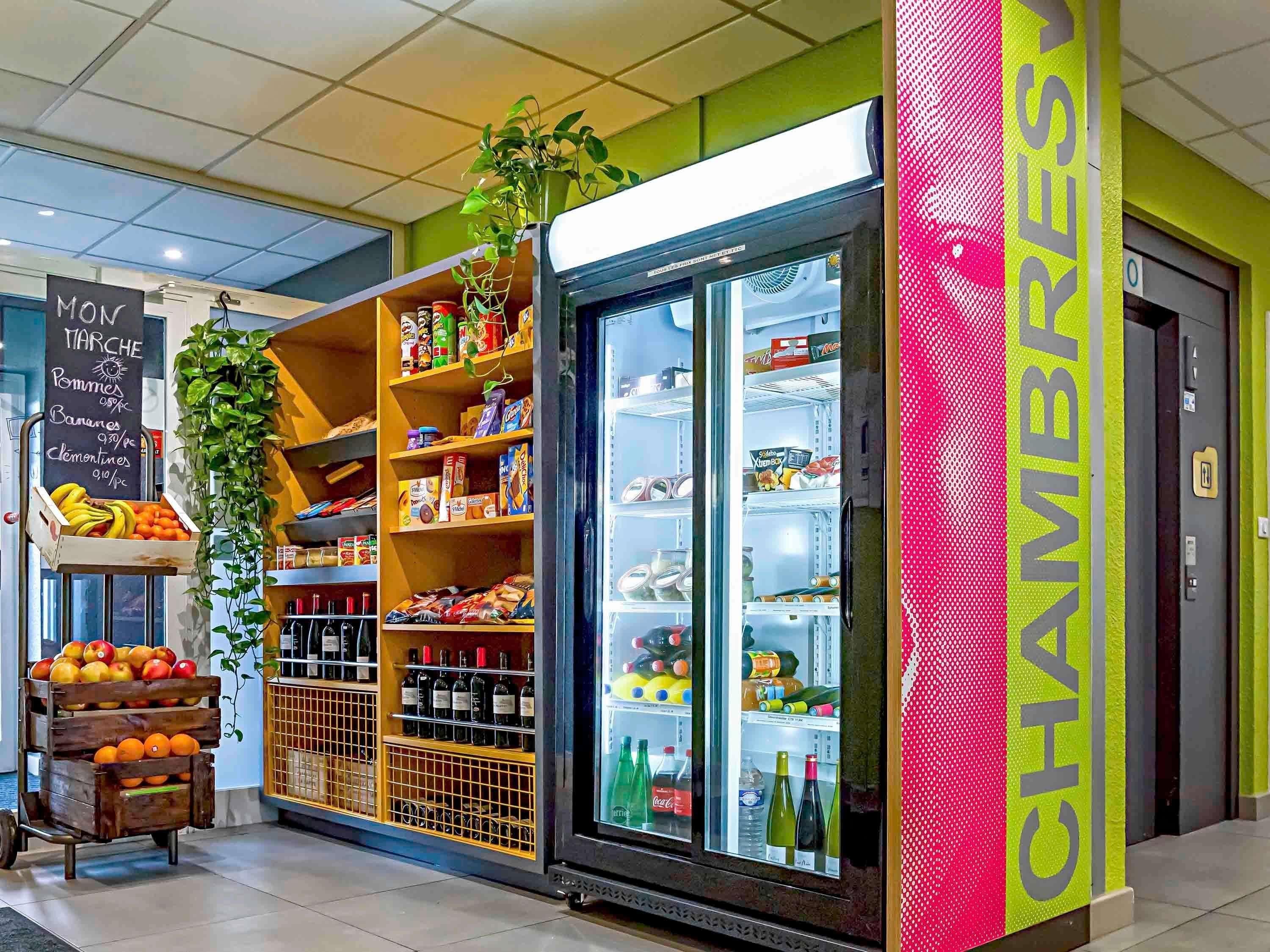 A store with a refrigerated display, shelves stocked with various products, and a chalkboard menu.