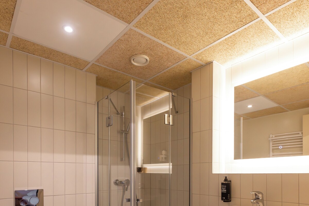 Een moderne badkamer met een douche met glazen wand, een wit wastafelmeubel en een grote spiegel.