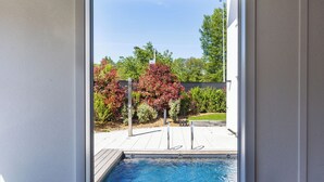 A room with a large window overlooking a swimming pool, a potted cactus, and two blue chairs. - ibis budget Strasbourg Sud Illkirch Geispolsheim (Geispolsheim)