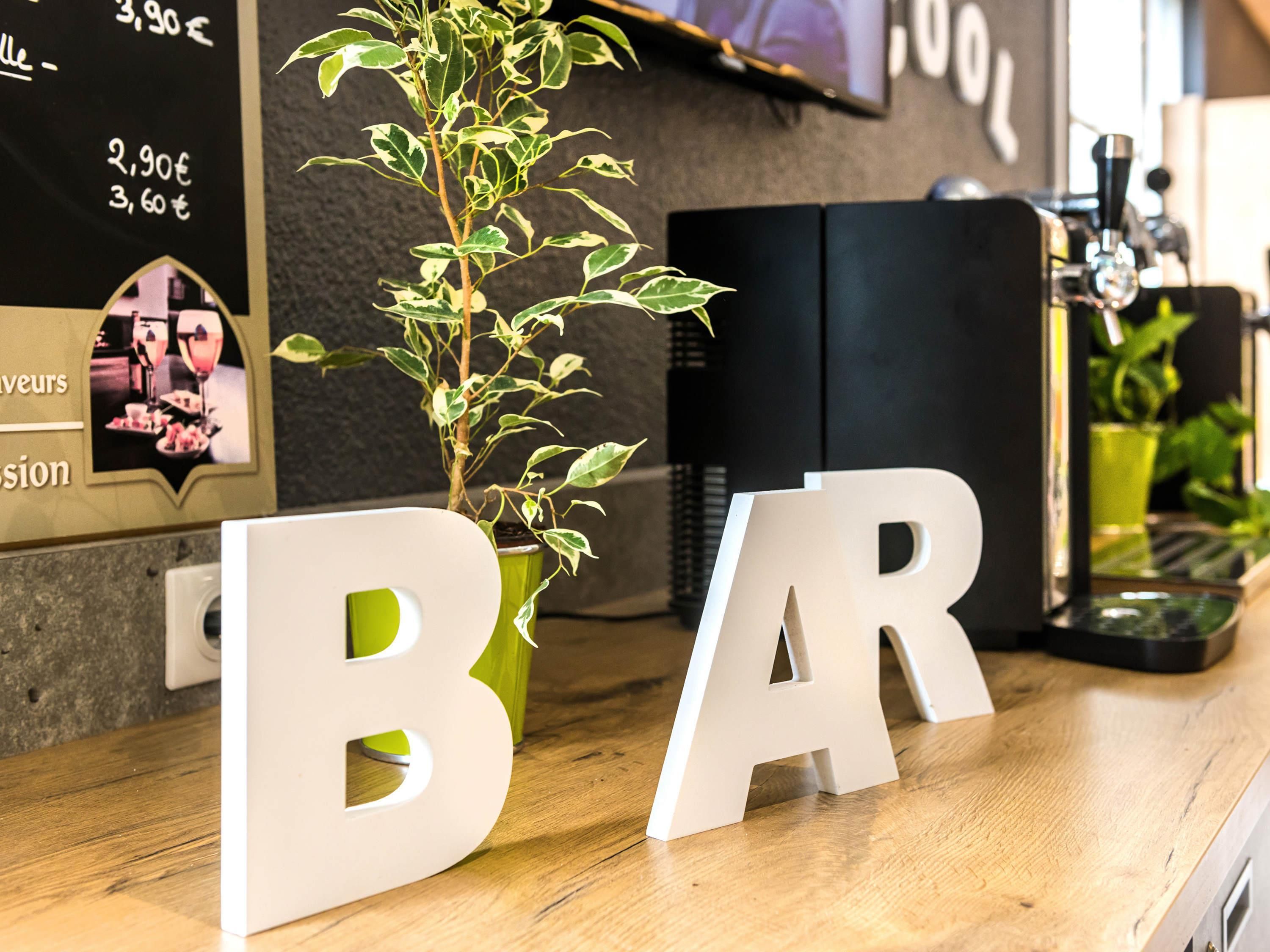 Zona de bar con planta en maceta y un menú en pizarra.