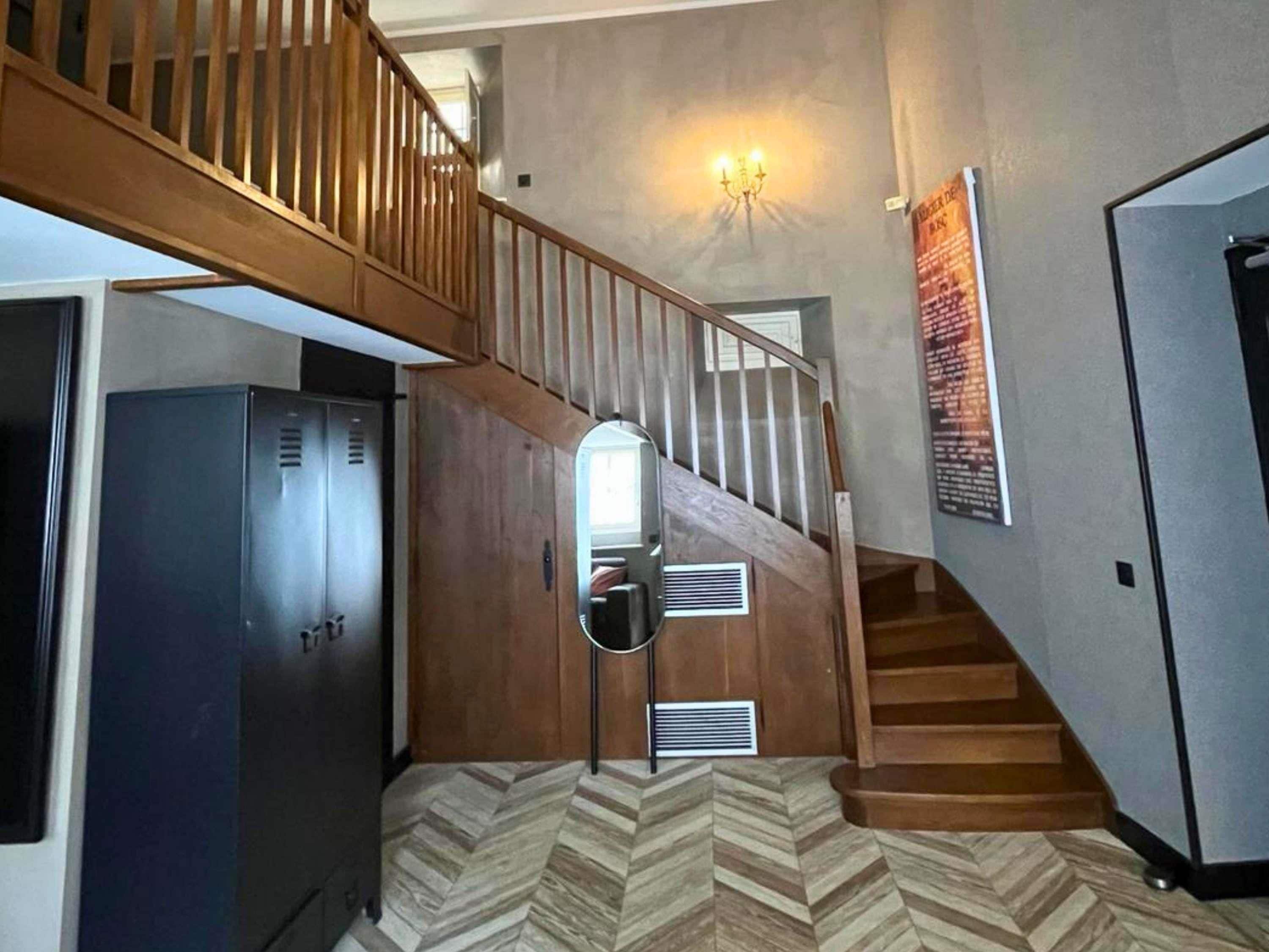 A staircase with wooden railings, a wall-mounted light fixture, and a patterned floor.