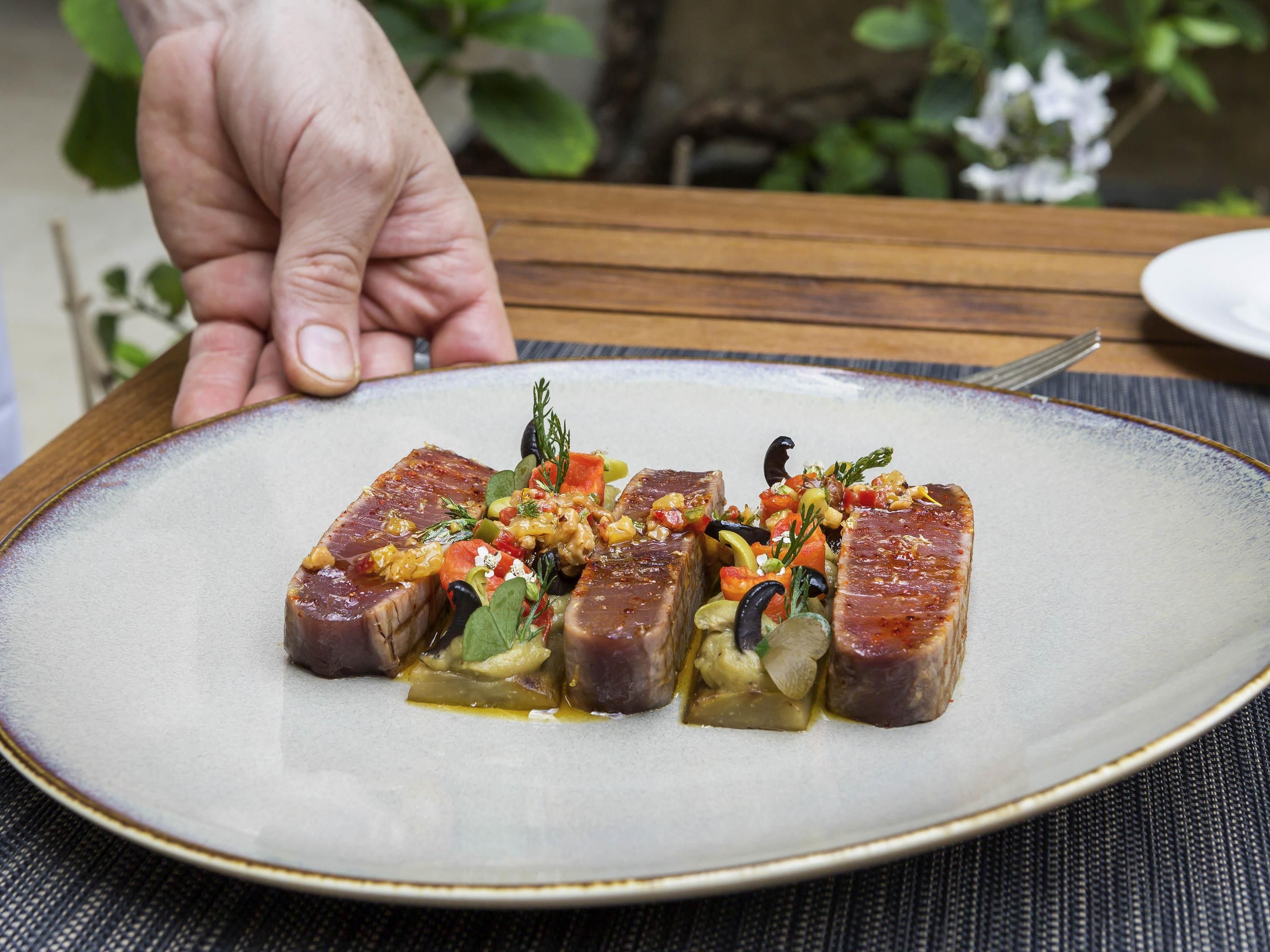 A plate of food with a hand reaching for it.