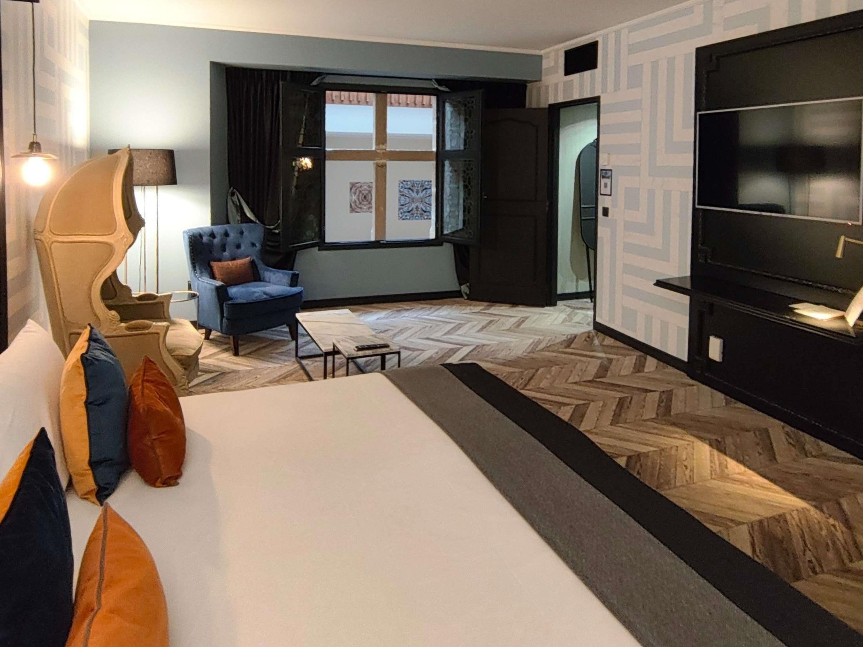 A hotel room with a bed, a chair, a TV, and a window with a view.