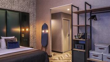 Een hotelkamer met een bed, een kledingkast, een spiegel, een bureau met een computer en een schoenenrek.