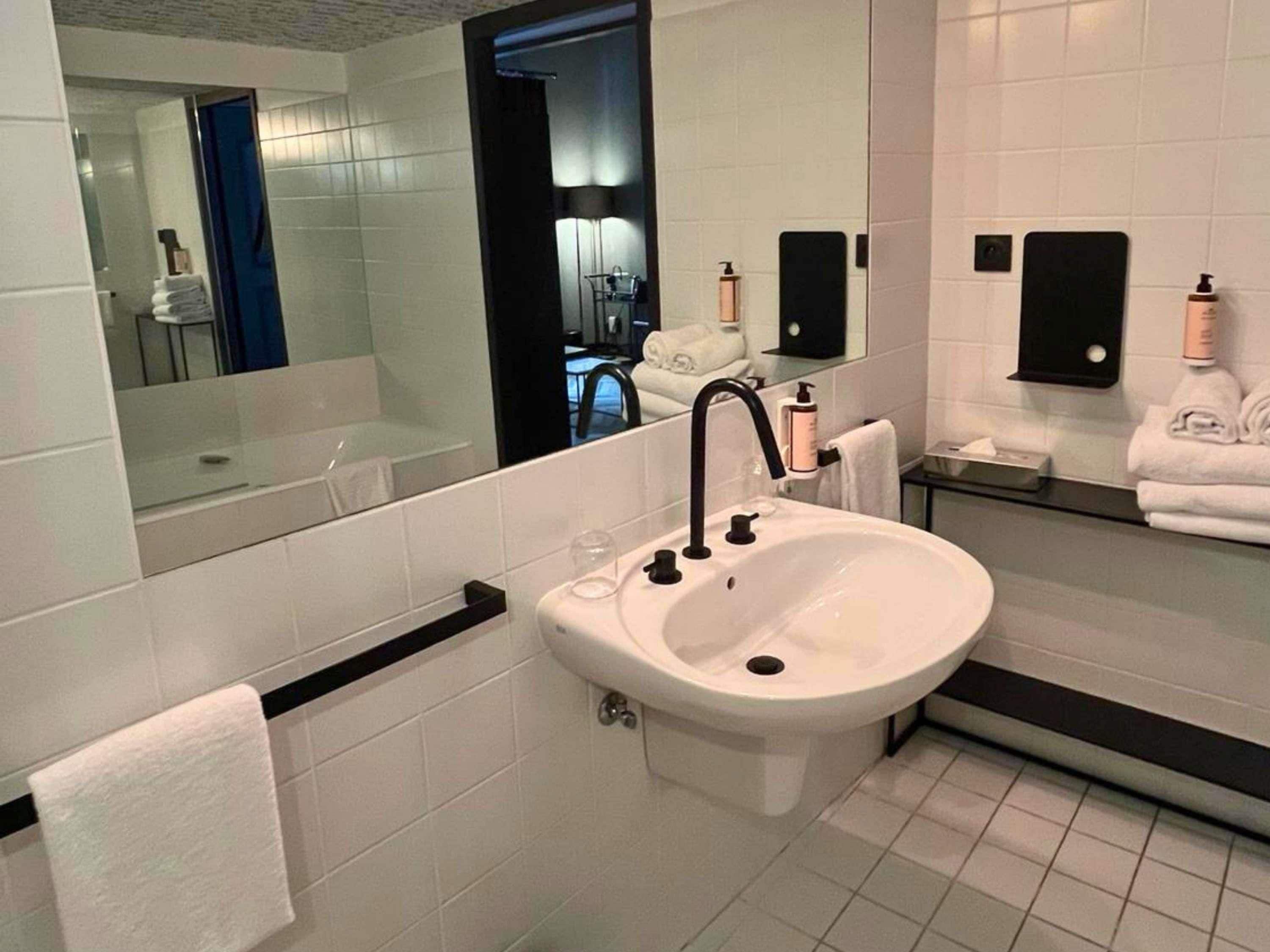 A modern bathroom with a white sink, black faucet, and a large mirror.