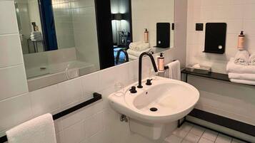 A modern bathroom with a white sink, black faucet, and a large mirror.