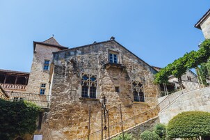 Un edificio de piedra con ventanas arqueadas y una escalera que lleva a un balcón.