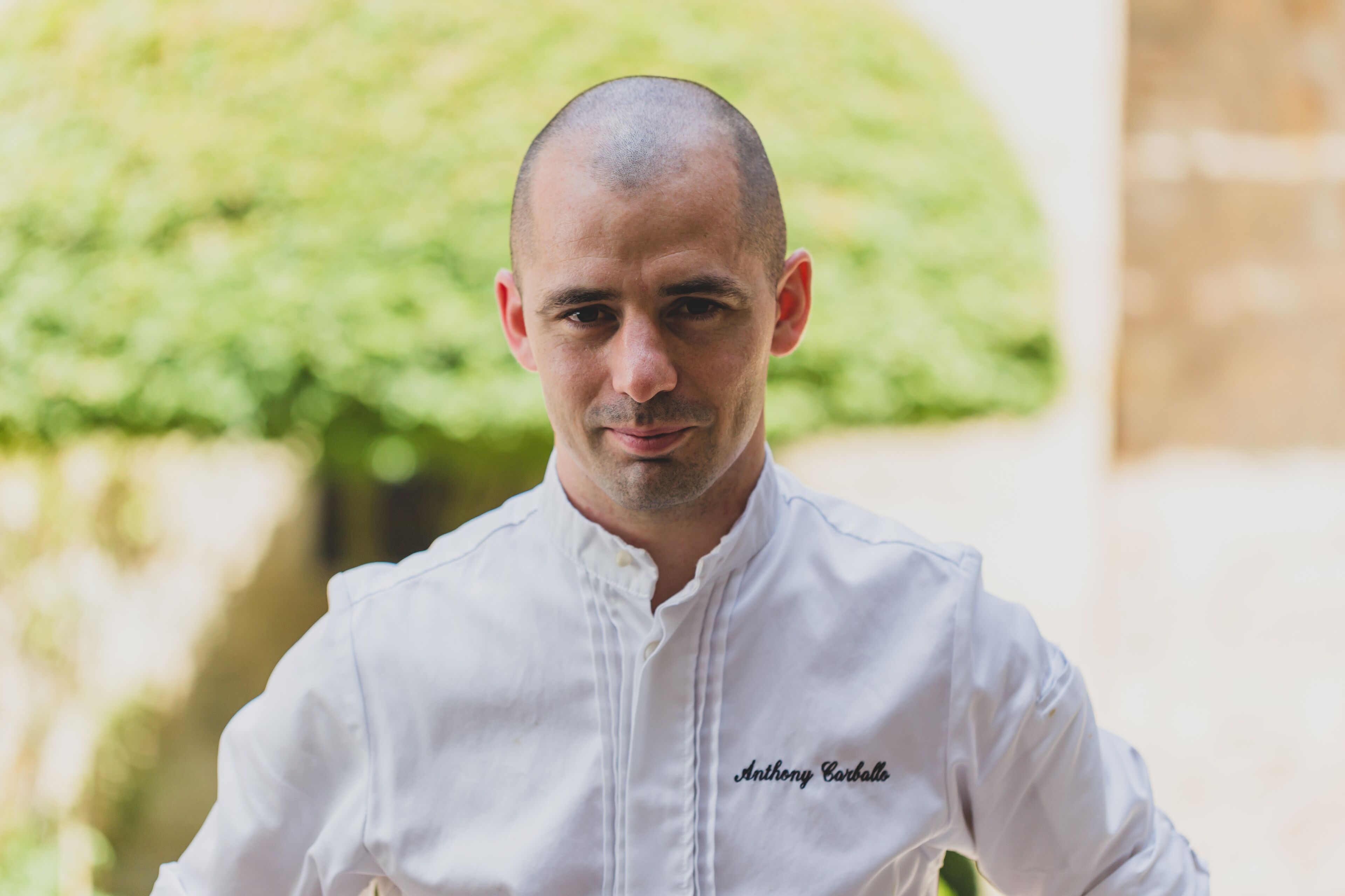 A person in a white chef's jacket with the name "Anthony Corbato" embroidered on it.