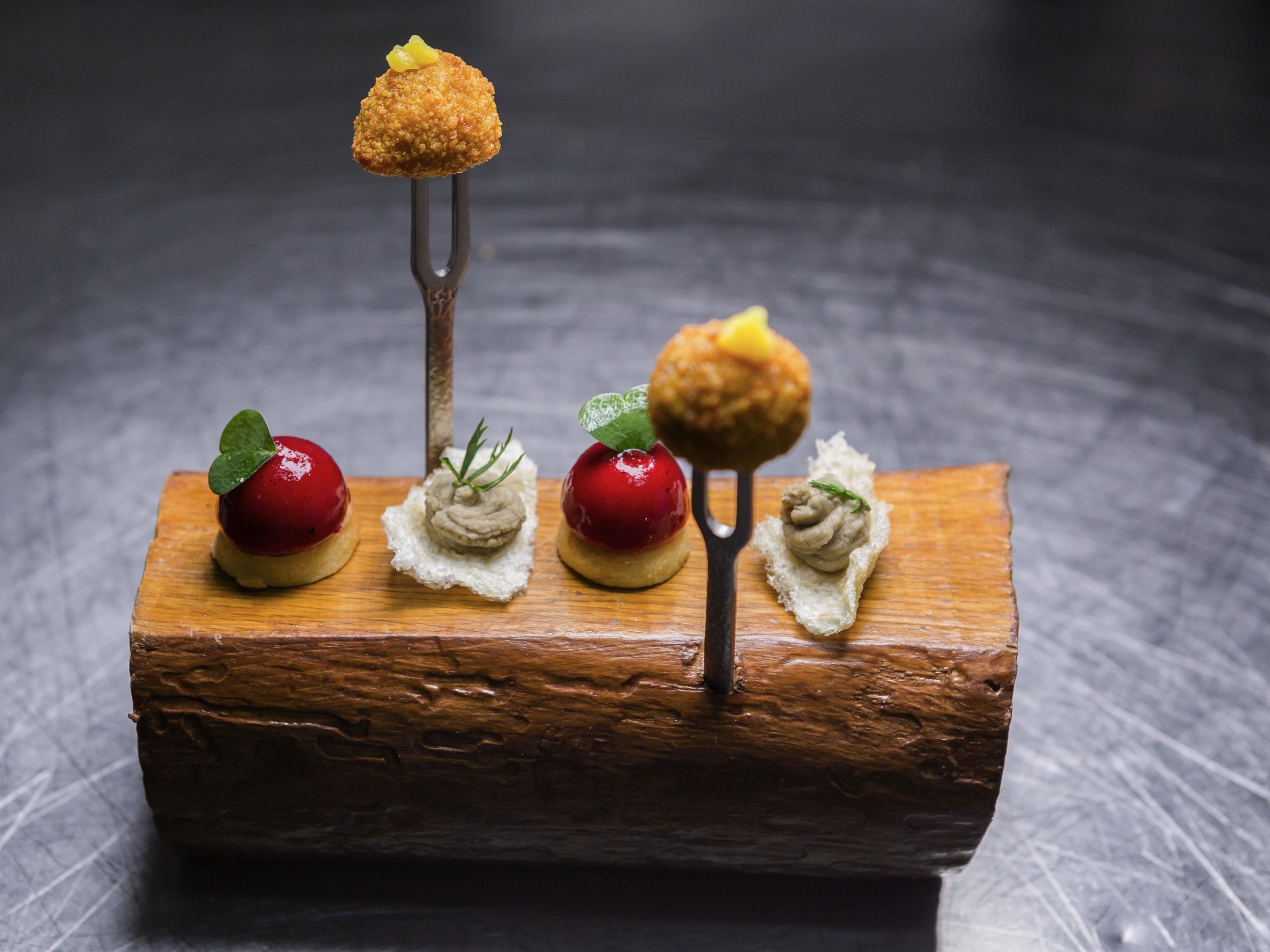 Een houten blok met vijf soorten eten, elk met een andere garnering.