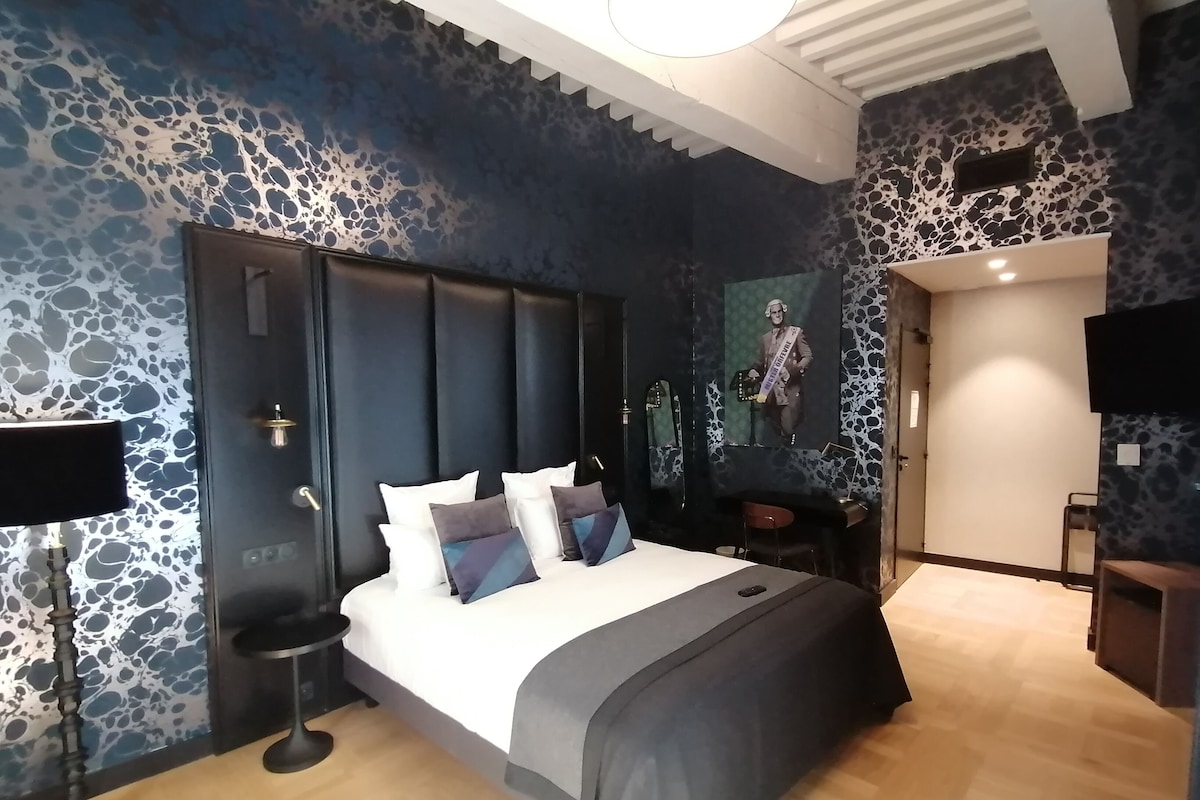 Ein modernes Schlafzimmer mit einem großen Bett, einem Nachttisch, einem Spiegel und einem an der Wand befestigten Fernseher.