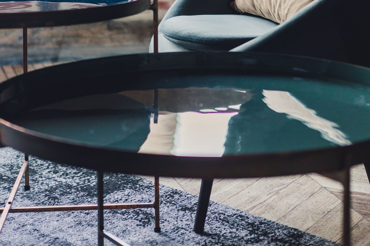 Ein modernes Interieur mit Backsteinwand, rundem Glastisch und grauem Sessel mit Kissen.