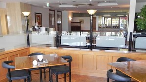 A restaurant with wooden tables and chairs, a counter, and a view of the street. - Shimabara Hakusan Hotel (Shimabara)