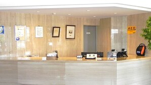 A reception desk with framed certificates, a GEORGIA brand coffee machine, and an AED sign. - Shimabara Hakusan Hotel (Shimabara)
