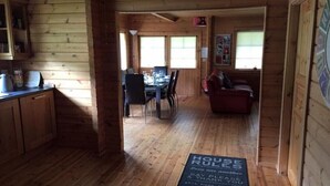 Interior de una cabaña de madera con comedor, cocina y sala de estar.