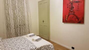 A bedroom with a bed, a green door, and a red artwork on the wall.