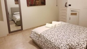 A bedroom with a bed, a mirror, a wardrobe, and a painting of a Buddha.