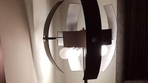 A floor lamp with a modern design, a wall-mounted picture frame, and a wooden cabinet.