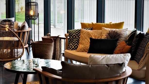 Een modern interieur met een bank, stoelen, een tafel en rieten manden.