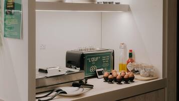 Una kitchenette con un tostador, una cafetera y una botella de aceite.