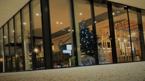 Een modern gebouw met grote raampartijen, een kerstboom versierd met lichtjes en een sneeuwpop.
