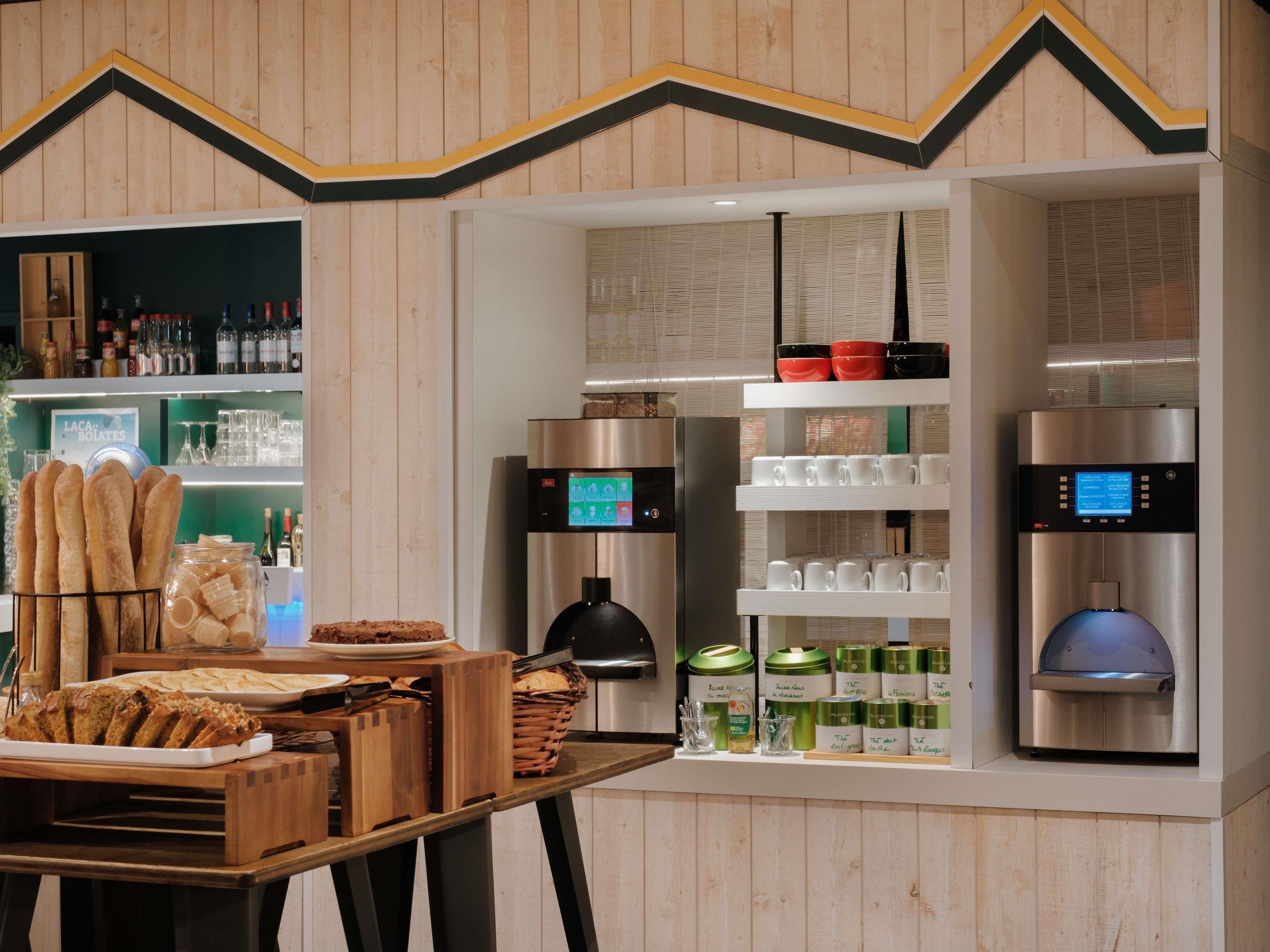 A modern kitchen with a wooden accent wall, a bread display, and a coffee machine.