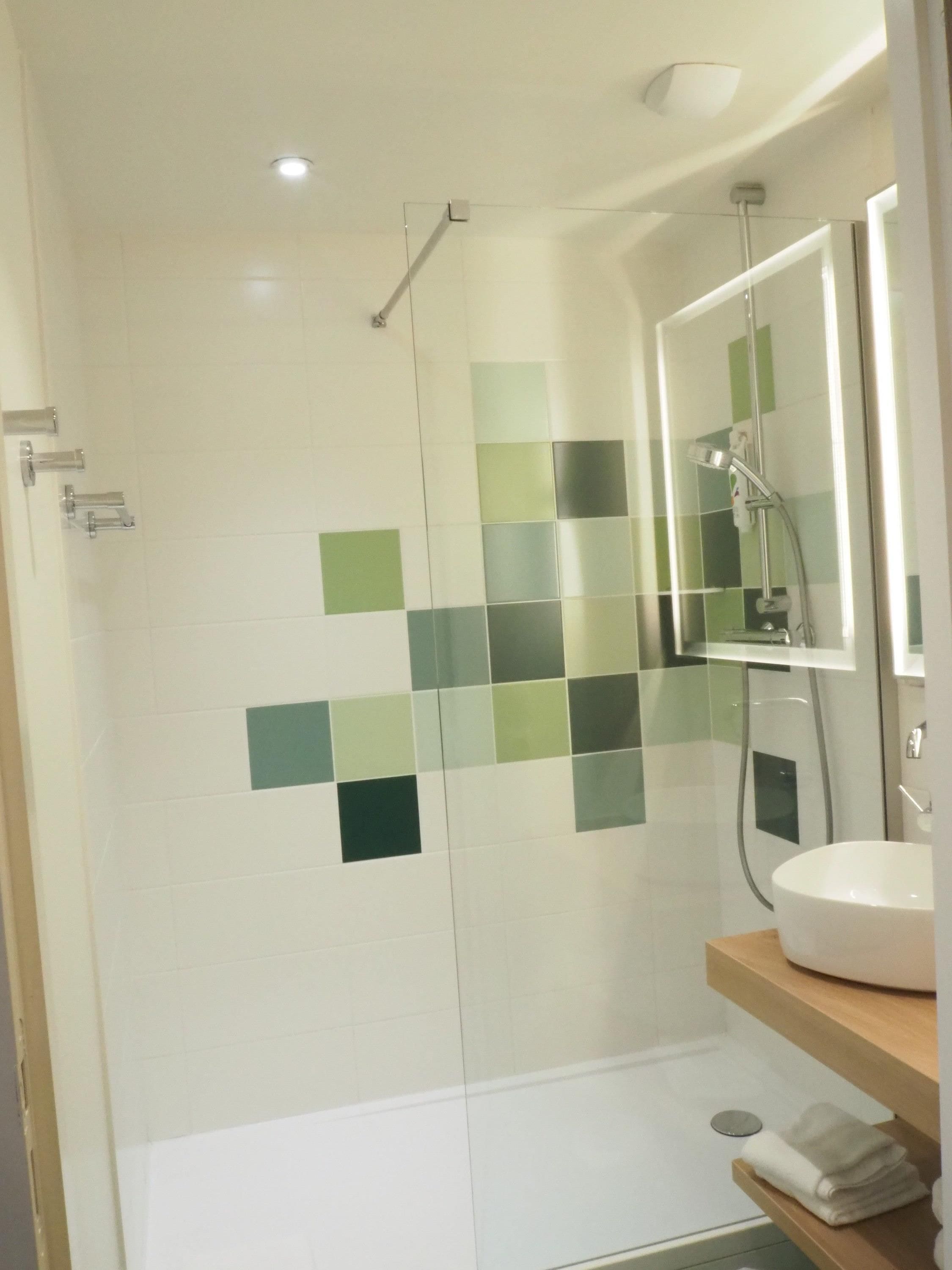 A bathroom with a shower, a sink, and a mirror.