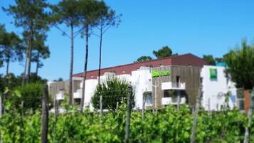 Un bâtiment avec un toit rouge et des murs blancs, entouré de verdure.