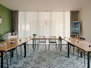 A conference room with a long table, chairs, and a poster on the wall. - ibis Styles Arcachon Gujan Mestras (Gujan-Mestras)