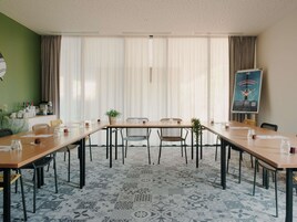 Un salón de conferencias con una larga mesa, sillas y un cartel en la pared.