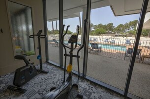 Una habitación con un ventanal grande, una bicicleta estática y una cinta de correr.