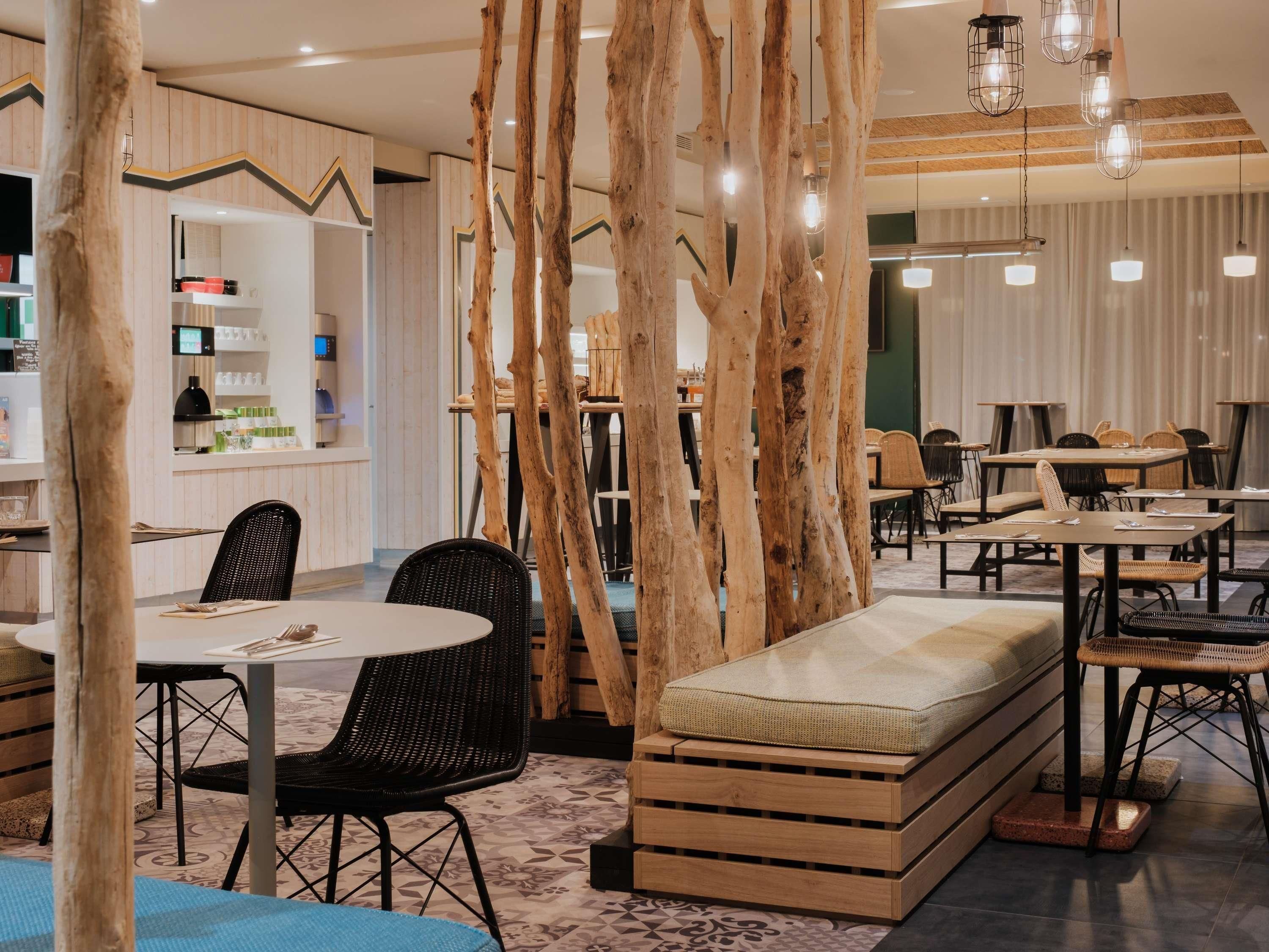 A modern dining area with wooden accents, round tables, and black wicker chairs.
