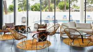 Een moderne lounge met rieten meubels, uitzicht op het zwembad en grote ramen.