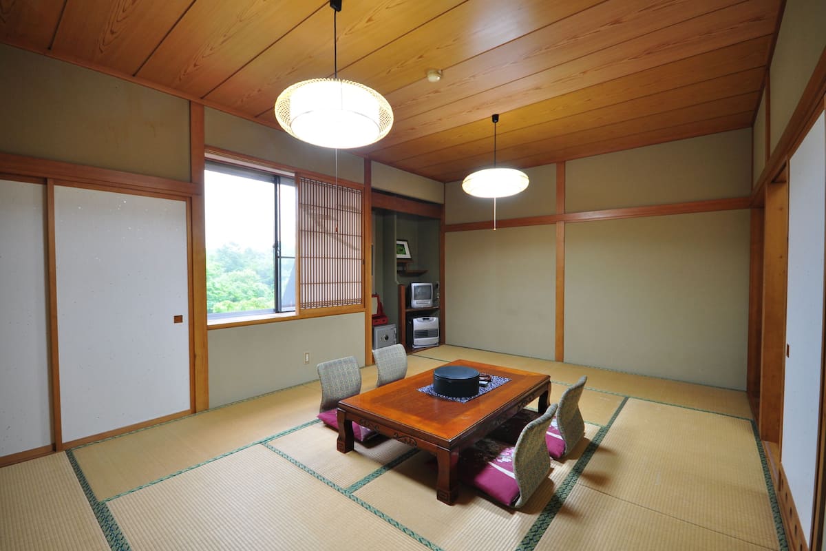 Um quarto japonês tradicional com tatames, uma mesa de madeira baixa e portas corrediças.
