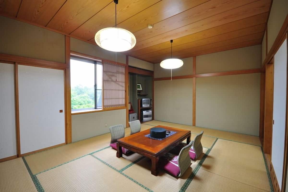 Um quarto japonês tradicional com tatames, uma mesa de madeira baixa e portas deslizantes.